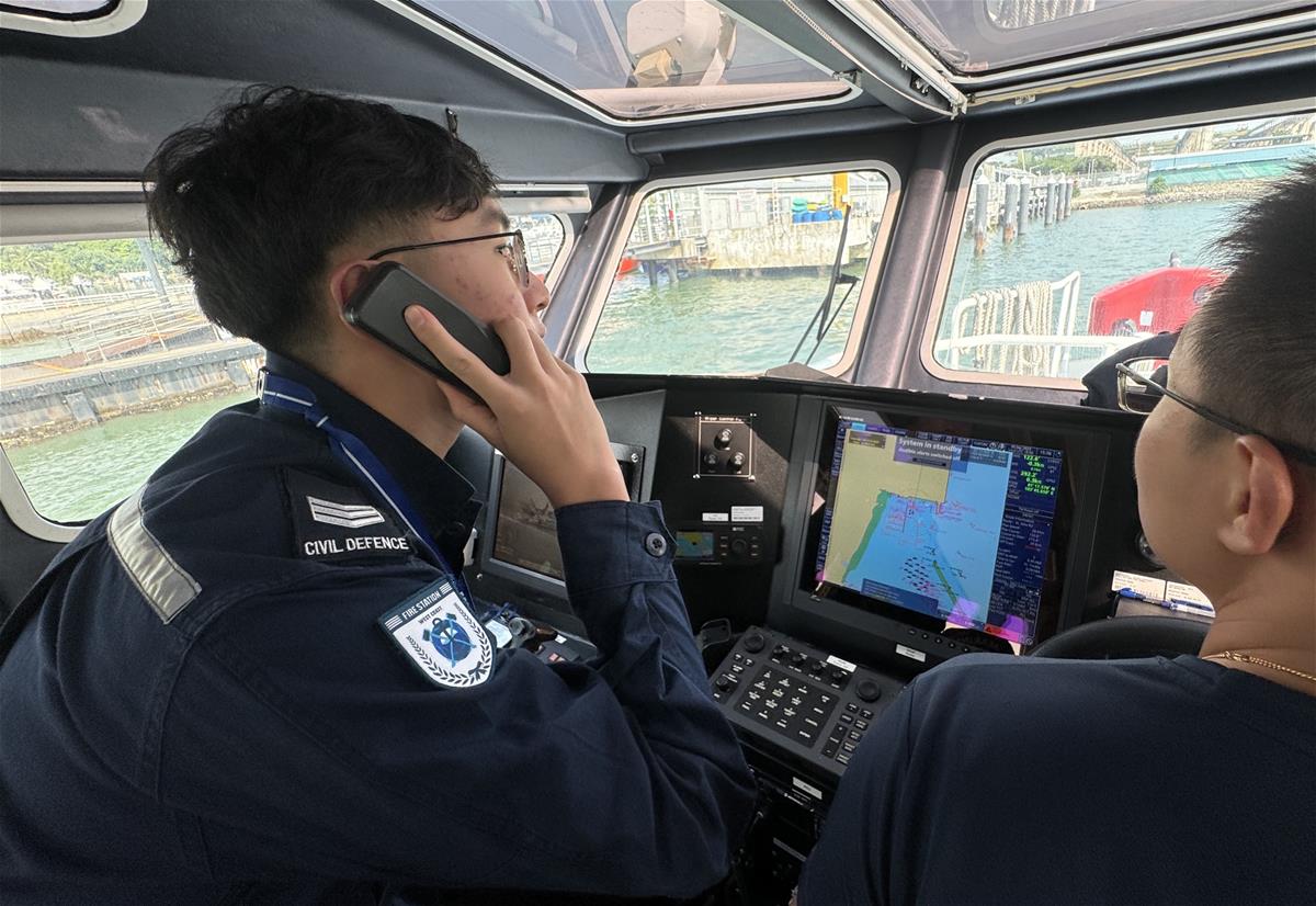 SGT2 Bowen (left) navigating a SCDF marine vessel during a routine exercise