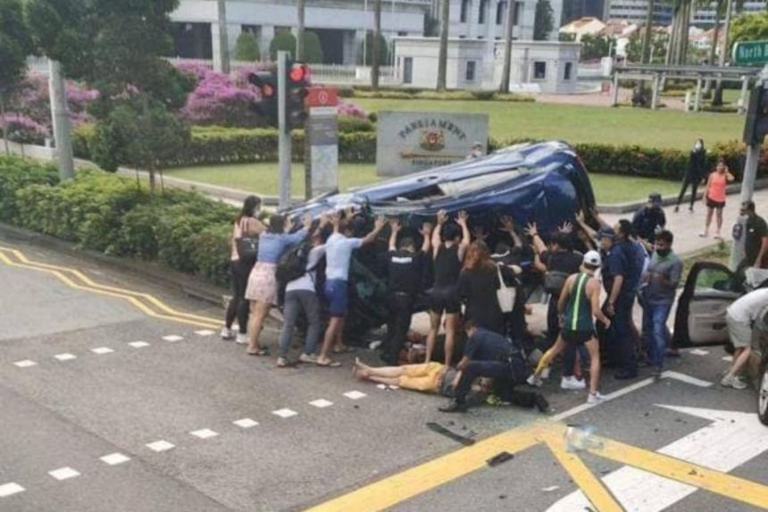 More than a dozen people stepping forward to lift the car. [Credit: The Straits Times]