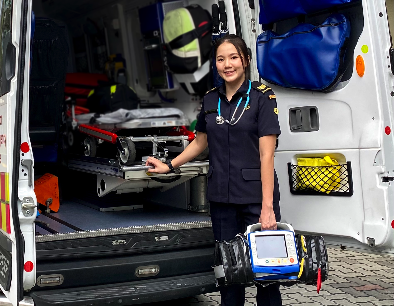Paramedic SGT2 Gwen Ong Sock Puay carrying the defribrillator, a device that restores a normal heartbeat by sending an electric pulse to the heart of a patient.